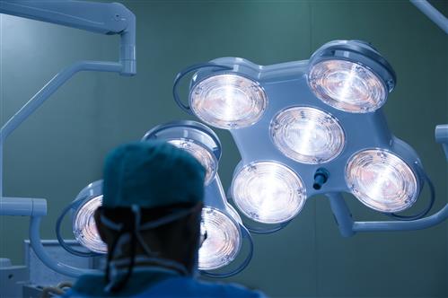 Silhouette of a surgeon with operating lights in the background
